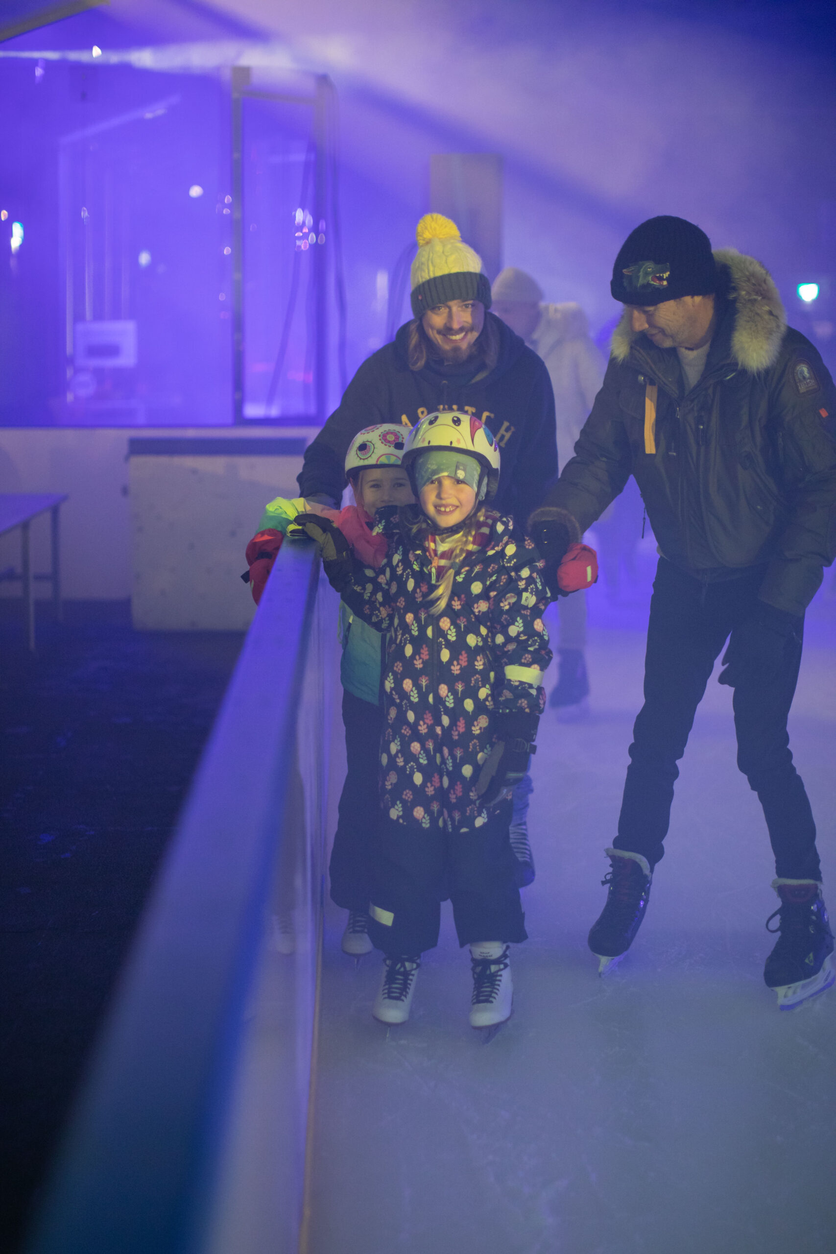 Familie mit Kind auf dem Eis an der Eisdisco im Schüwo Park Wohlen, im blauen Licht der Lichtshow